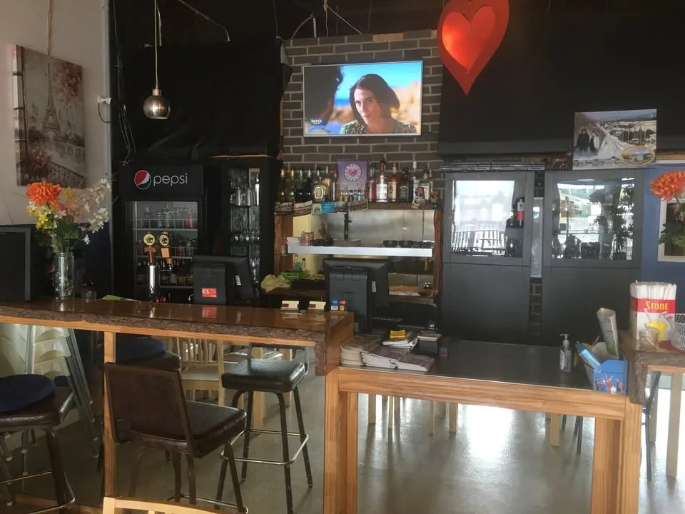 Le comptoir et le bar en bois du restaurant, mur de brique et fleurs